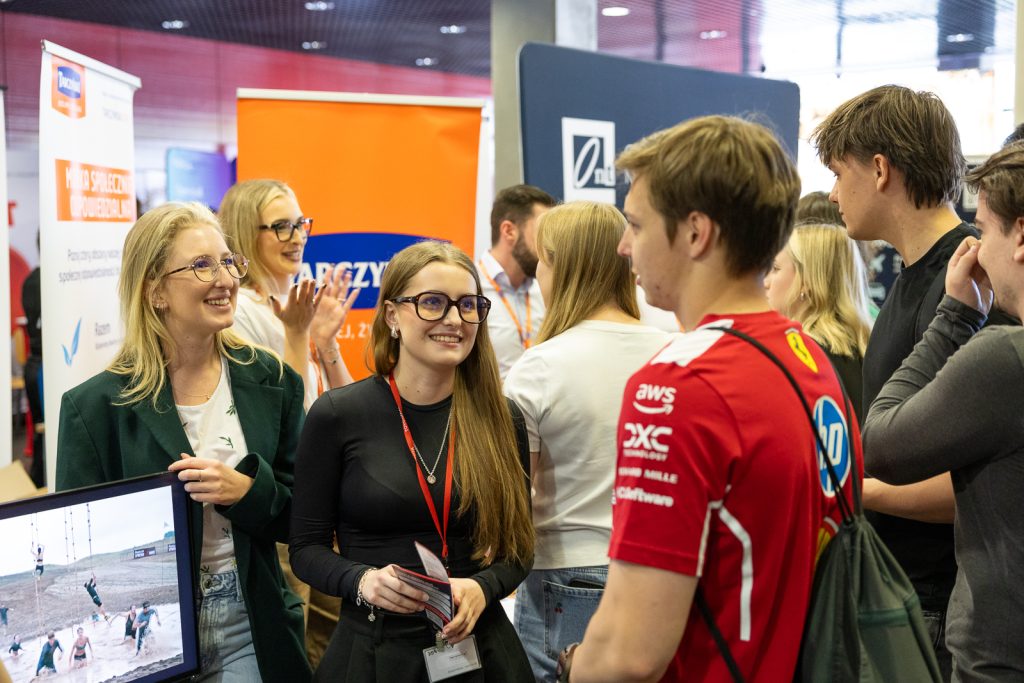 zdjęcie przedstawiające grupę młodych ludzi rozmawiających i uśmiechających się